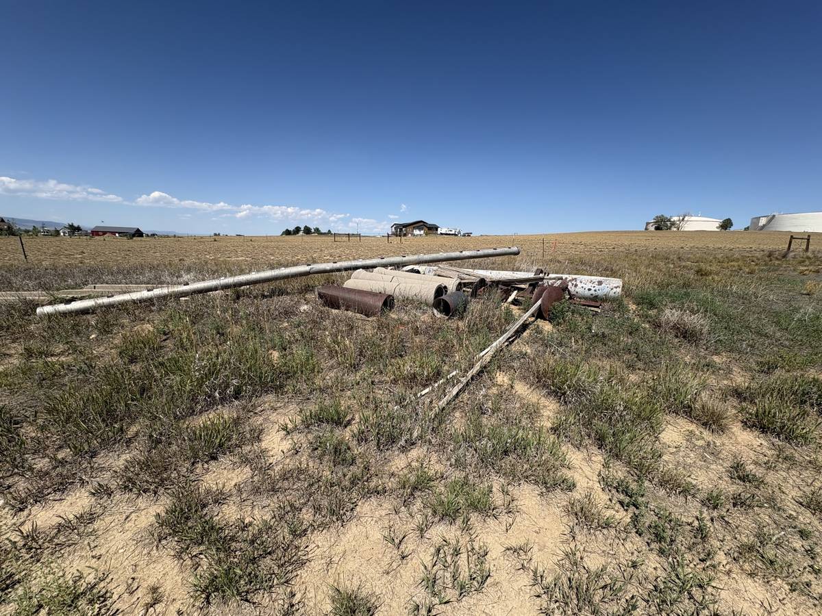 Pile of old irrigation pipe and scrap metal on a farm property before junk removal in Northern Colorado