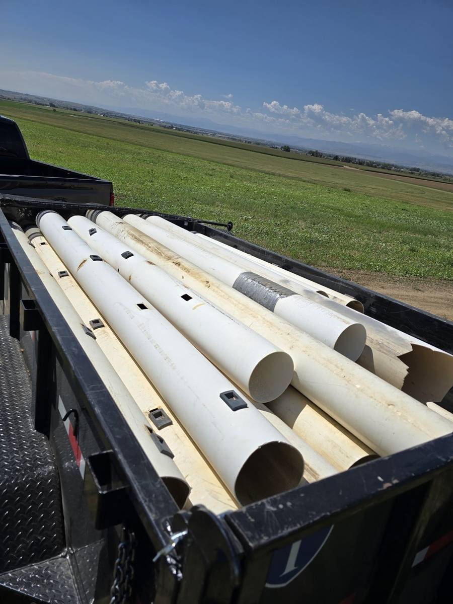 Dump trailer loaded with irrigation pipe during a farm junk removal job in Northern Colorado