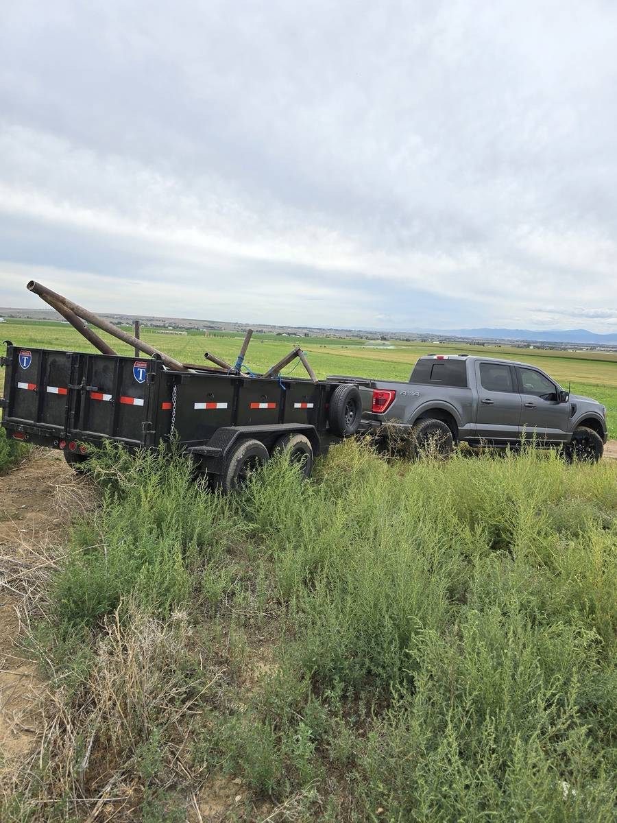 Northern Colorado Junk Removal truck and trailer loaded with scrap pipe at a farm property