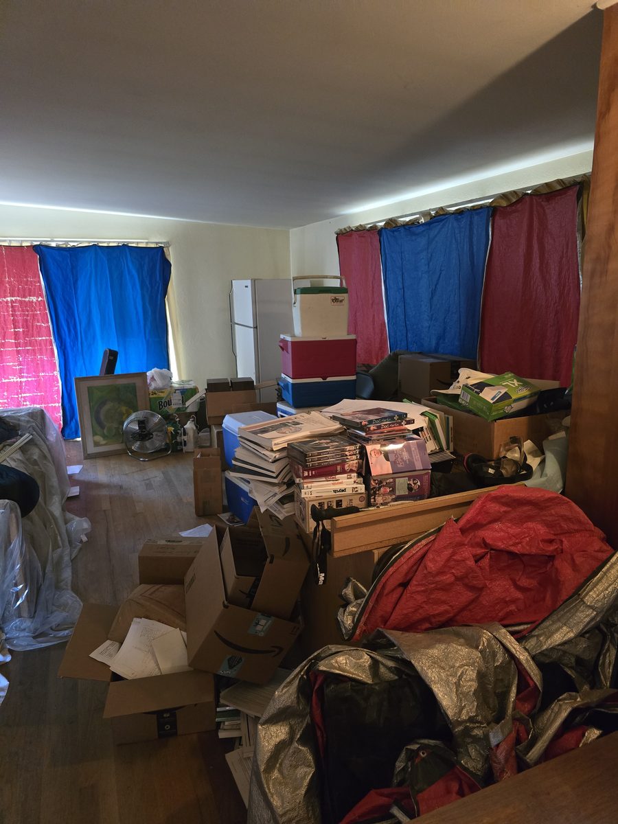 Living room cluttered with boxes and belongings before cleanout in Northern Colorado