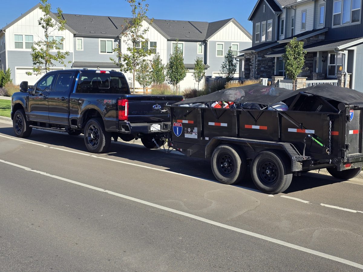 Northern Colorado Junk Removal truck and trailer loaded with bagged items on a residential street